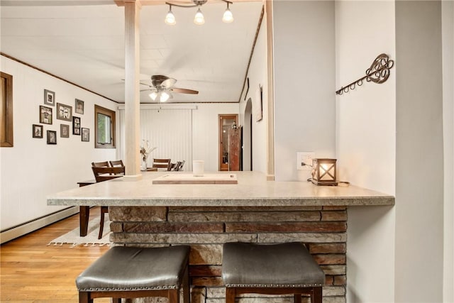 bar featuring a ceiling fan, baseboard heating, baseboards, ornamental molding, and wood finished floors
