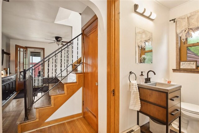 staircase with a ceiling fan, a wealth of natural light, wood-type flooring, and arched walkways