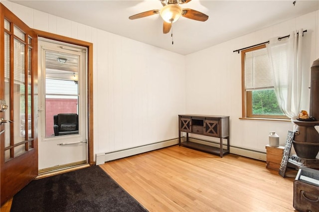 misc room featuring light wood finished floors, ceiling fan, and a baseboard heating unit