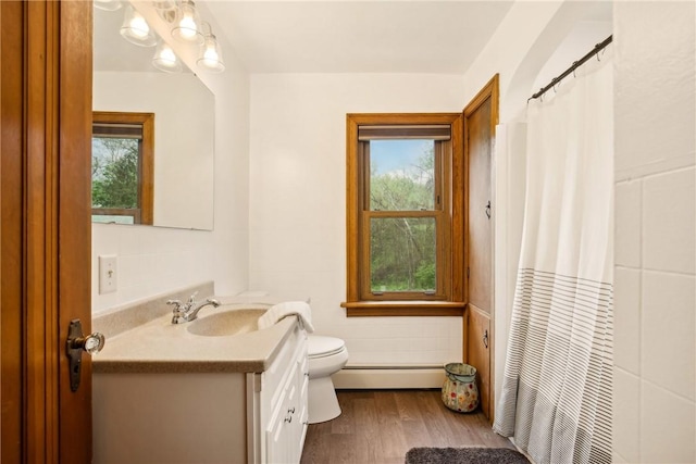 full bathroom with toilet, a shower with curtain, wood finished floors, vanity, and baseboard heating
