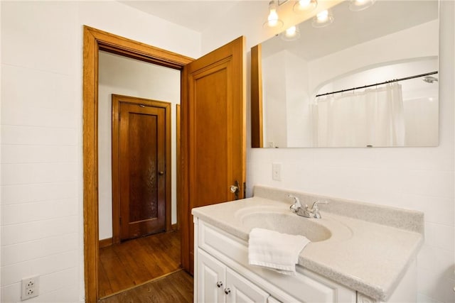 full bath with a shower with curtain, vanity, and wood finished floors