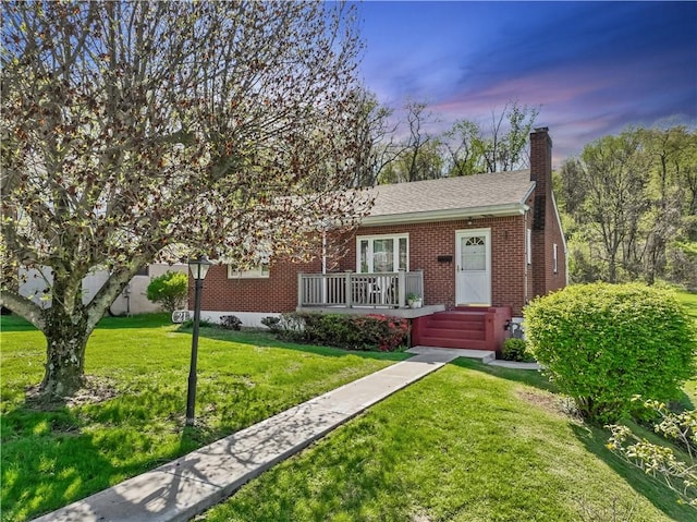 view of front of property with a chimney, brick siding, and a front lawn