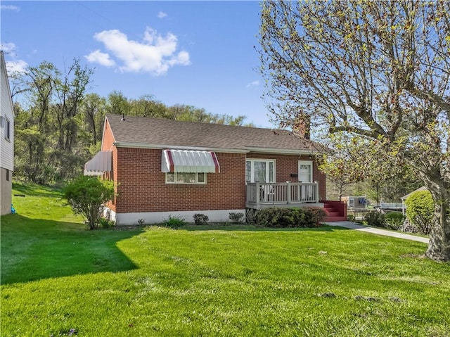 bungalow-style house featuring a front lawn, brick siding, a chimney, and a deck