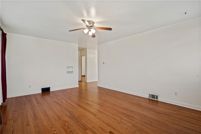 spare room featuring visible vents, wood finished floors, baseboards, and ceiling fan
