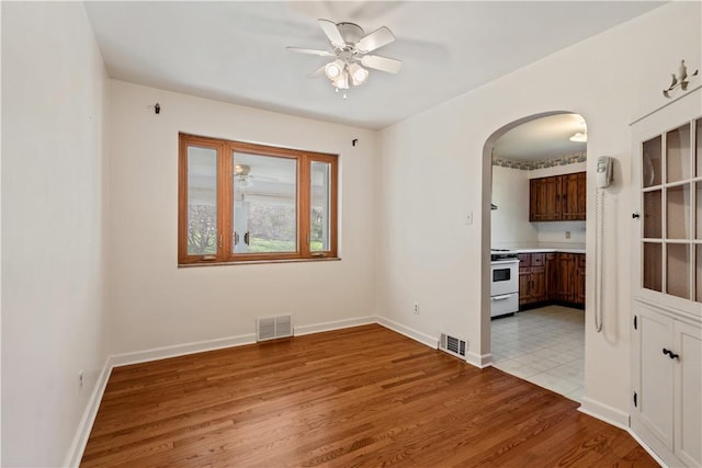 spare room featuring ceiling fan, arched walkways, and visible vents