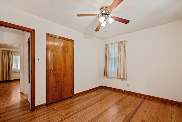 unfurnished bedroom with multiple windows, light wood-type flooring, a closet, and baseboards
