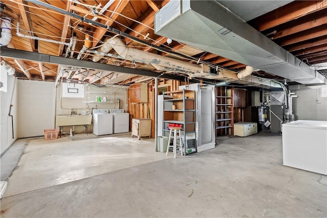 basement with heating unit, refrigerator, a sink, gas water heater, and independent washer and dryer