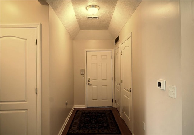 doorway to outside featuring dark wood-style flooring, a textured ceiling, visible vents, and baseboards