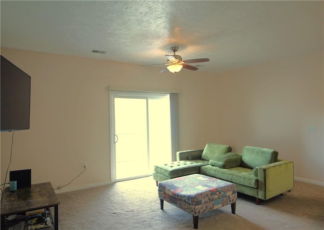 living room featuring light colored carpet, visible vents, baseboards, and a ceiling fan