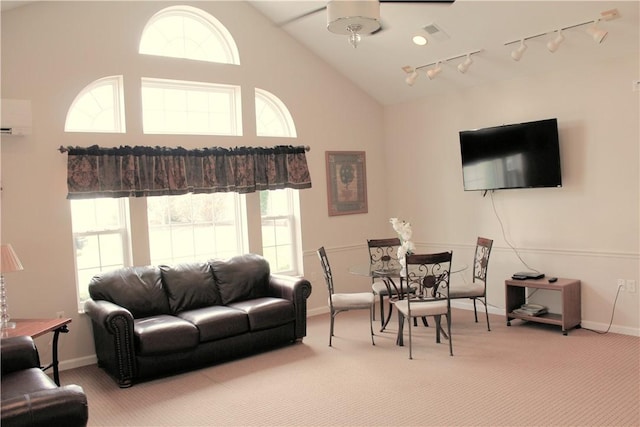 living area featuring track lighting, a wall mounted air conditioner, baseboards, and light colored carpet