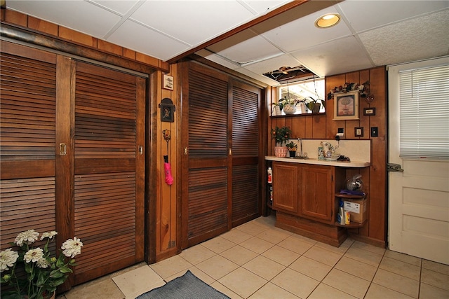 bar featuring light tile patterned floors, wood walls, a paneled ceiling, and recessed lighting