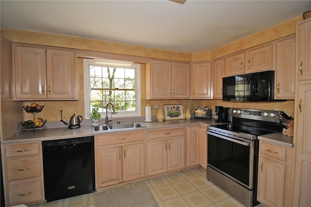 kitchen featuring black appliances, light countertops, light brown cabinets, and a sink