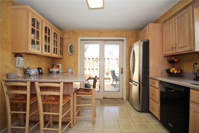 kitchen with light countertops, glass insert cabinets, freestanding refrigerator, light brown cabinets, and dishwasher