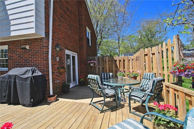 deck featuring fence, a grill, and outdoor dining space