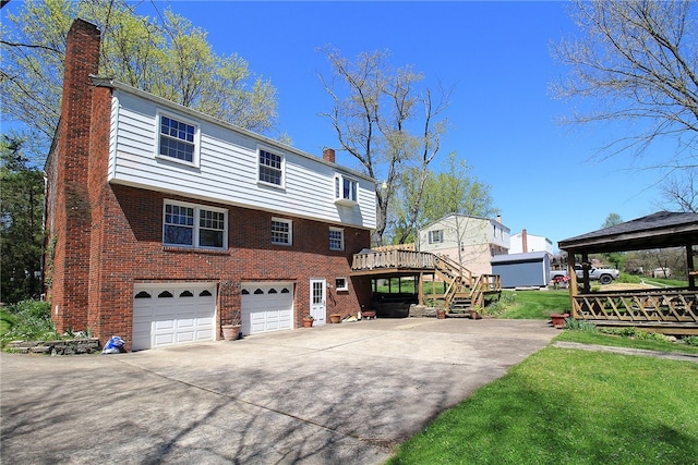 back of house with a chimney, brick siding, an attached garage, and concrete driveway