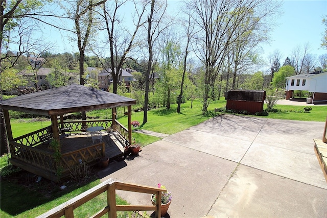 view of patio / terrace with a gazebo, a wooden deck, an outdoor structure, and a storage unit