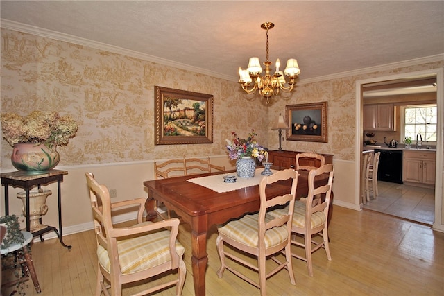 dining space with wallpapered walls, crown molding, wainscoting, light wood-style floors, and a chandelier