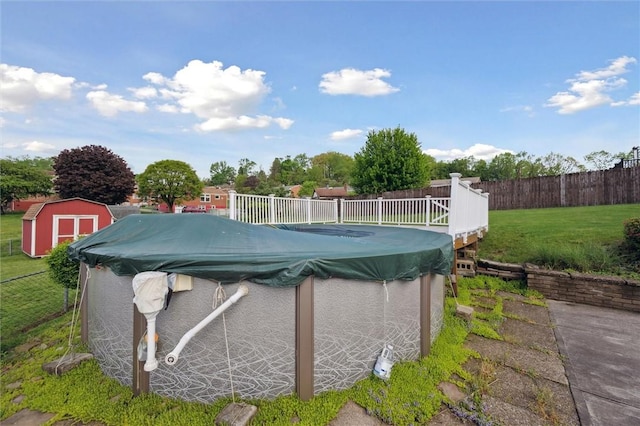 view of swimming pool with a storage shed, fence, an outdoor structure, a yard, and a fenced in pool