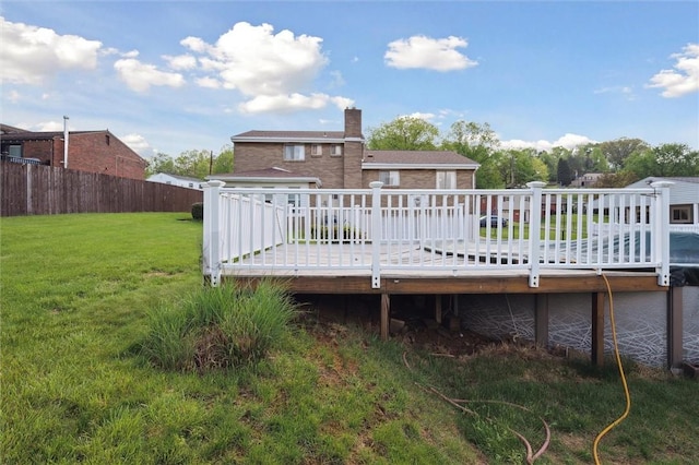 rear view of house featuring a yard, fence, a wooden deck, and a chimney
