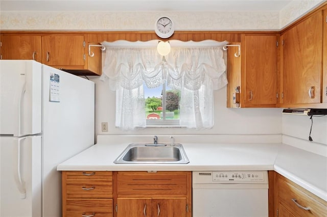 kitchen with light countertops, brown cabinets, a sink, and white appliances