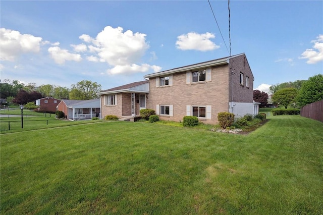 back of house with fence, brick siding, and a lawn