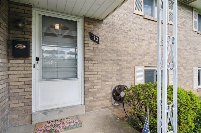view of exterior entry featuring brick siding