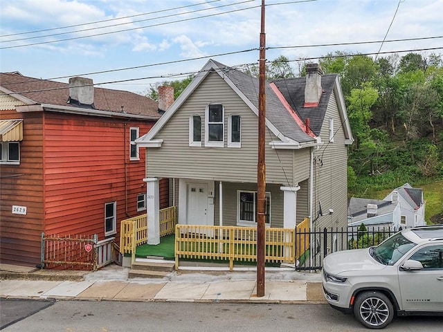 view of front facade with a porch, fence, and a chimney