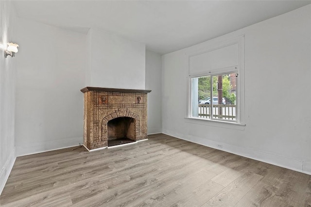unfurnished living room with wood finished floors, a fireplace, and baseboards