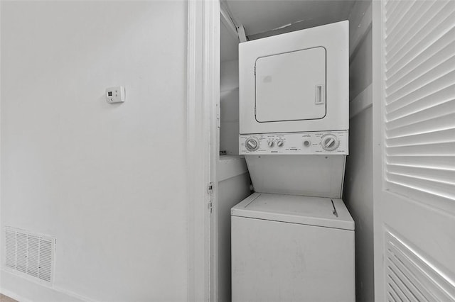 washroom featuring laundry area, stacked washer / drying machine, and visible vents