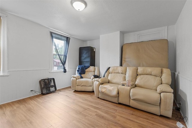 living area featuring light wood finished floors and a wainscoted wall