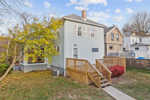 back of property featuring a chimney, central AC unit, a lawn, a deck, and stairs