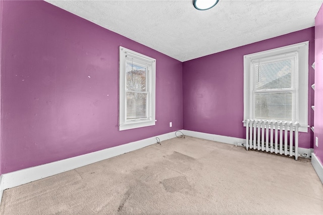 carpeted spare room with radiator, a textured ceiling, and baseboards