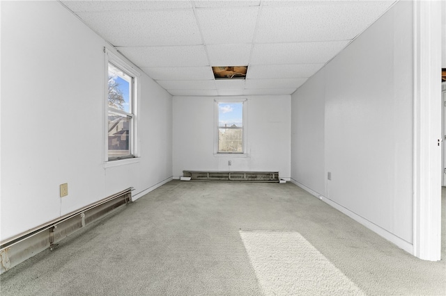 carpeted spare room with a paneled ceiling, baseboard heating, and healthy amount of natural light