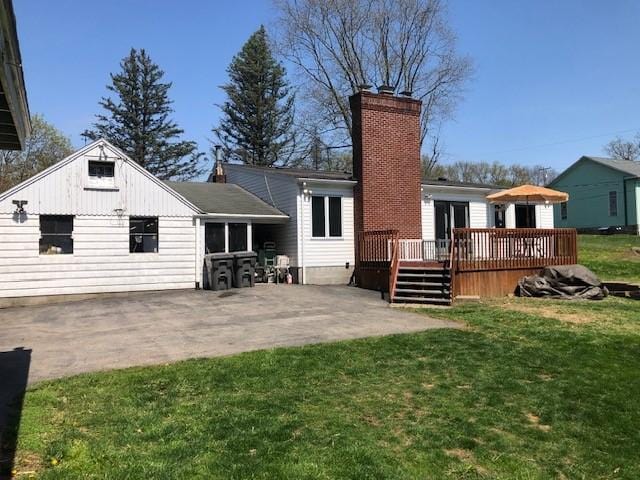 rear view of property featuring a lawn, a deck, a patio, and a chimney