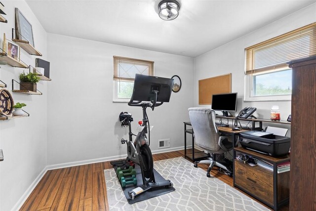 home office featuring baseboards, visible vents, and wood finished floors