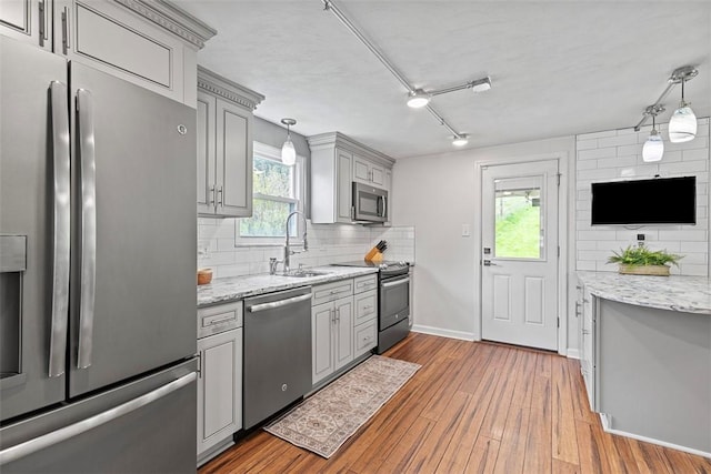 kitchen featuring decorative backsplash, appliances with stainless steel finishes, gray cabinetry, and wood finished floors