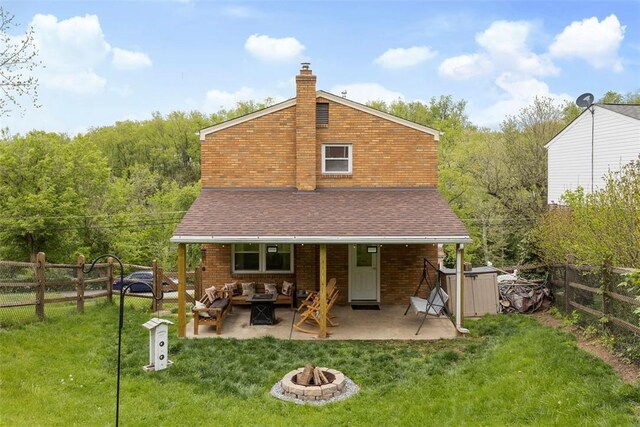 rear view of house with an outdoor living space with a fire pit, a lawn, and a fenced backyard