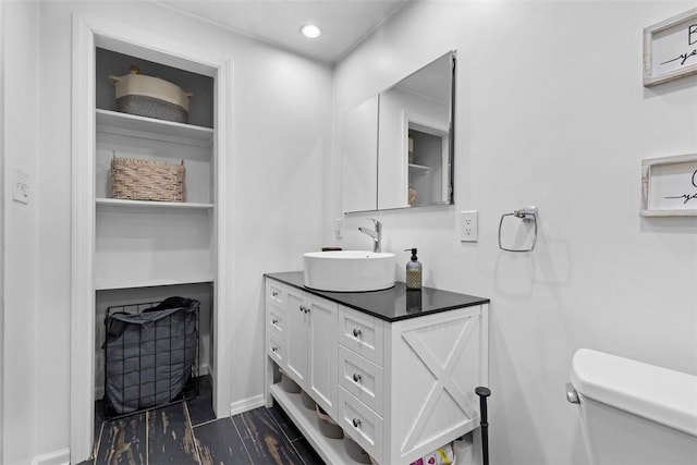 bathroom featuring vanity, toilet, baseboards, and recessed lighting