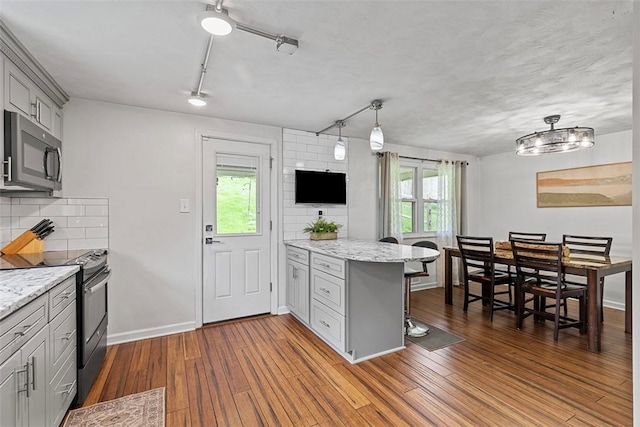 kitchen with stainless steel microwave, a peninsula, black / electric stove, and plenty of natural light