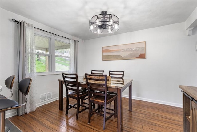 dining room with a notable chandelier, baseboards, visible vents, and dark wood finished floors