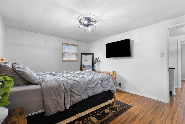 bedroom with visible vents, wood finished floors, and baseboards