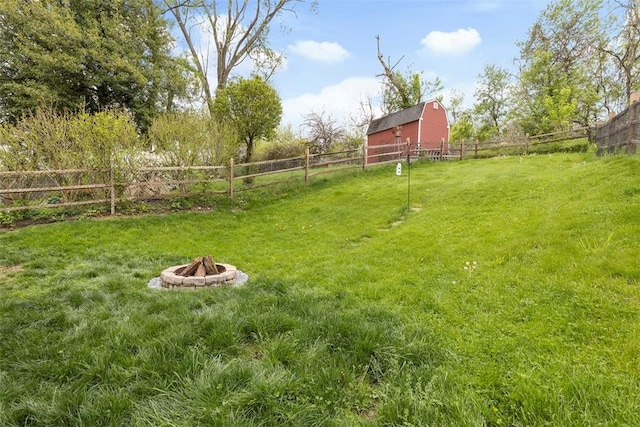 view of yard with a fire pit, fence, and a barn