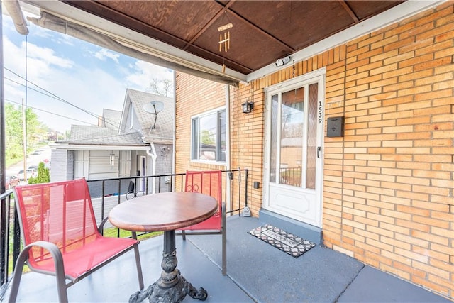 entrance to property featuring a balcony, brick siding, and covered porch
