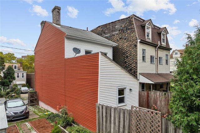 view of side of home featuring a chimney and fence