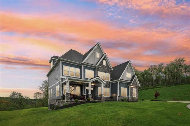 craftsman-style house featuring a yard, stone siding, and board and batten siding