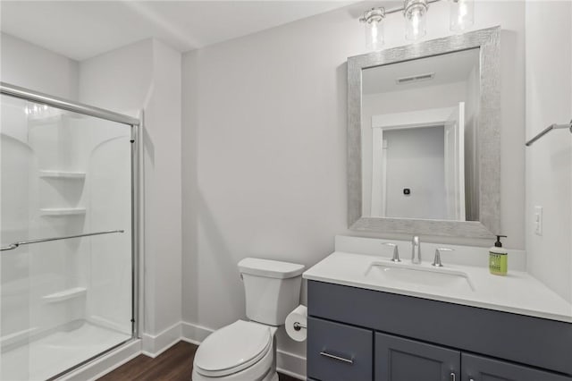 bathroom featuring toilet, wood finished floors, vanity, visible vents, and a shower stall