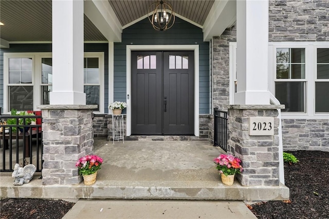 doorway to property with covered porch and stone siding