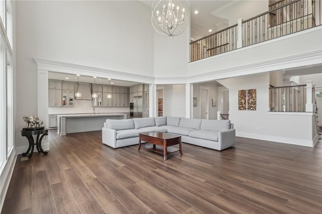 living room featuring a chandelier, dark wood-type flooring, baseboards, and a high ceiling