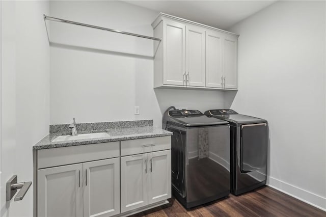 clothes washing area featuring baseboards, a sink, cabinet space, separate washer and dryer, and dark wood-style floors