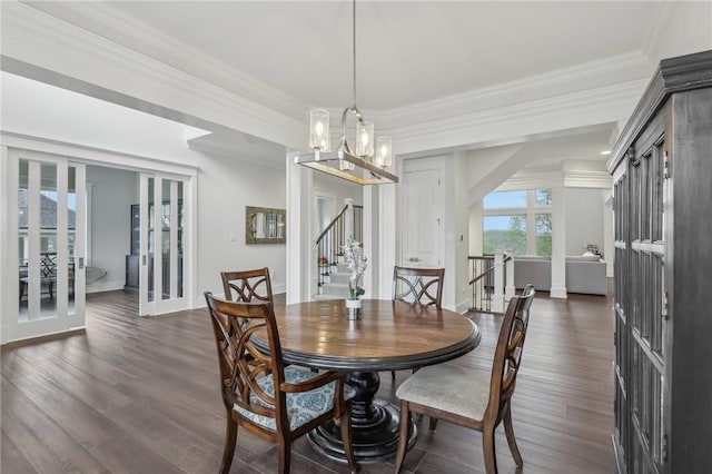 dining room featuring dark wood finished floors, a chandelier, ornamental molding, and stairs